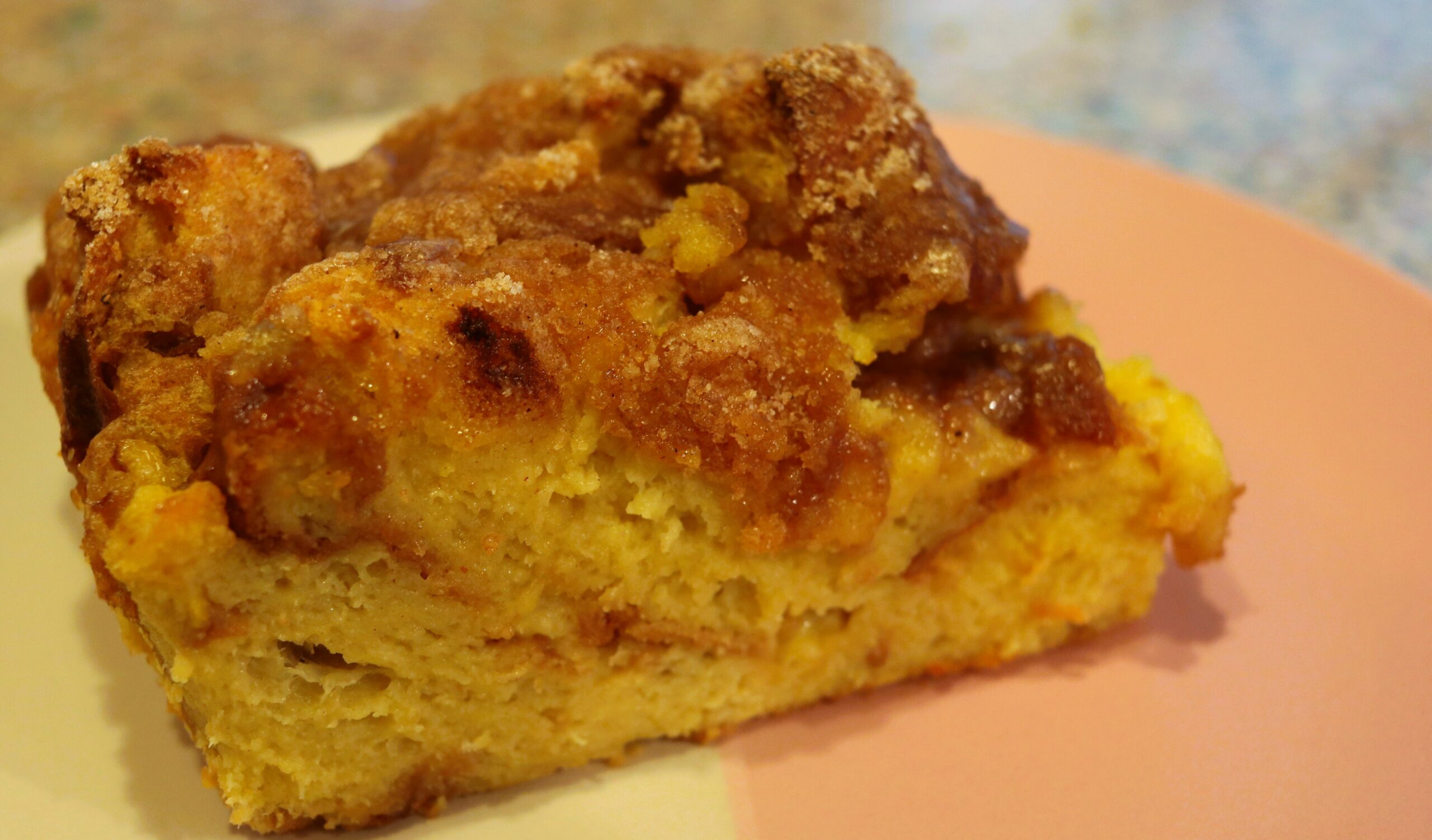 Piece of baked French toast sitting on a pink and white plate.