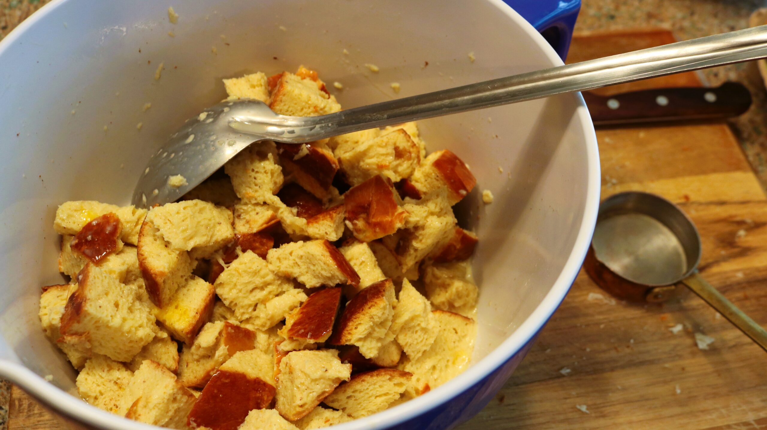 Brioche bread in a large bowl being mixed with wet ingredients