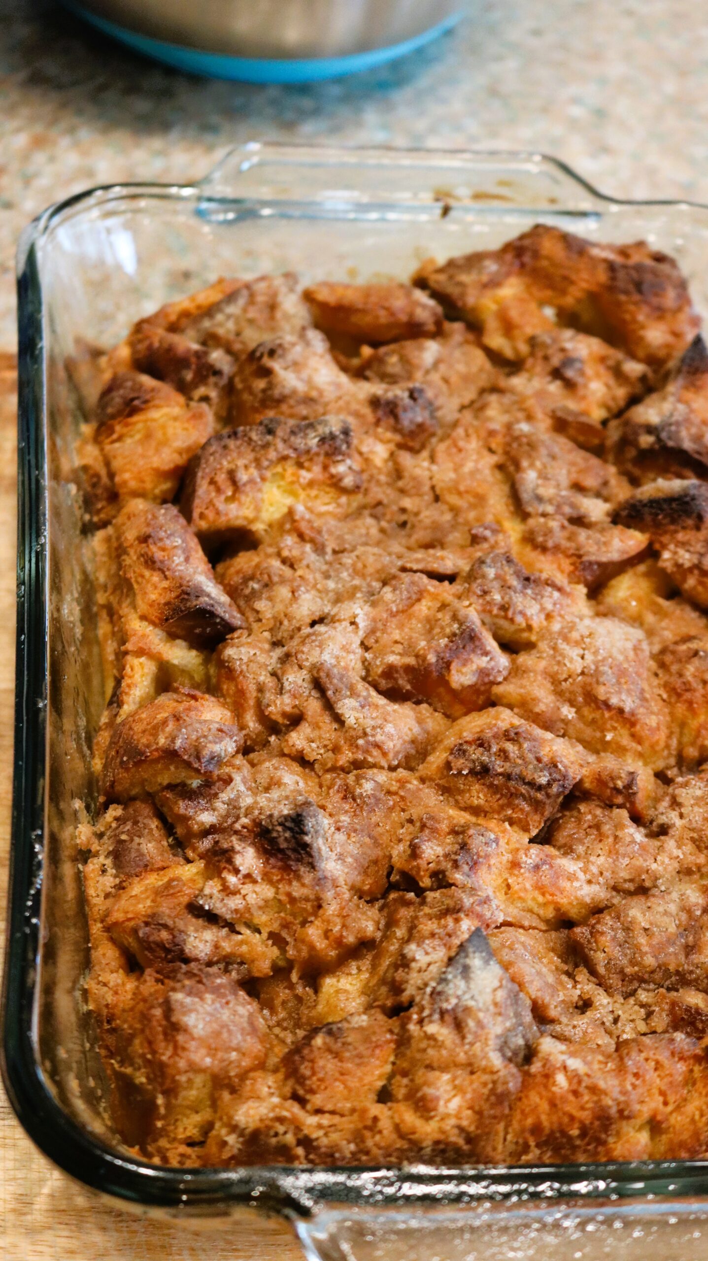 Quarter of the baked french toast in a glass pan sitting on the counter.