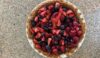 Mixed berry pie with strawberries, blackberries, blueberries, and raspberries in a graham cracker crust. Pie is sitting in a white pie plate on the counter.