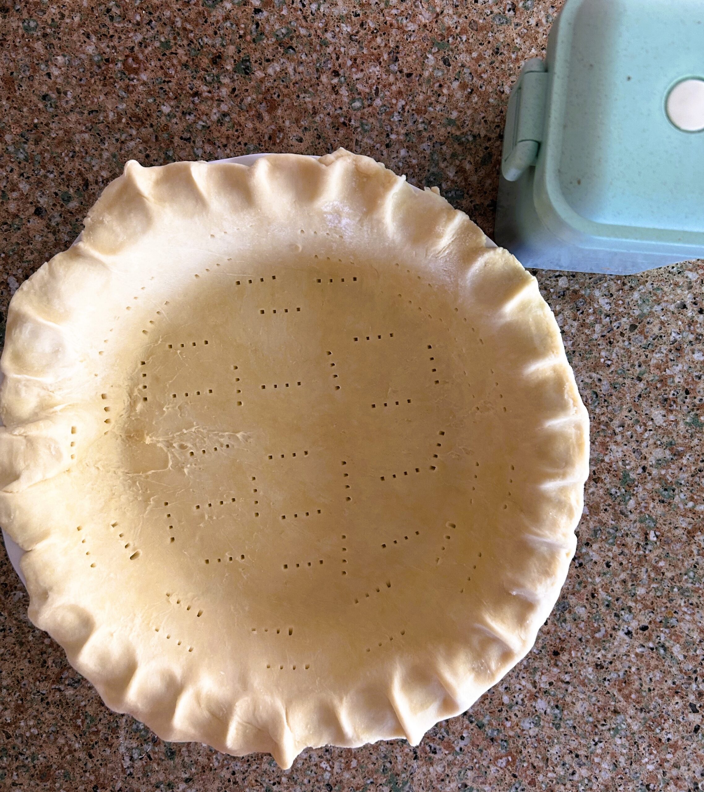 Single pie dough in pie plate on a counter with pie weights box in top right corner
