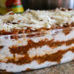 Layered lasagna with mozzarella, ricotta, and parmesan cheese with meat red sauce.