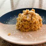 Saffron risotto positioned on a blue/white plate dusted with parmesan.