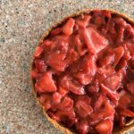fresh strawberry pie in graham cracker crust sitting on a granite counter.